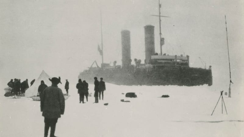 Старая фотография: во льдах стоит большой пароход с двумя трубами, на снегу люди и палатка