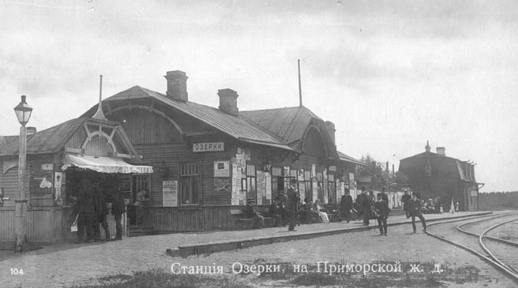 Старая фотография: деревянная станция с навесом, платформа, люди и деревья вокруг