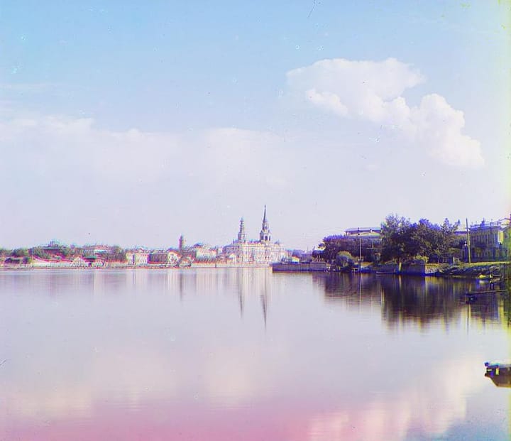 Цветная фотография начала XX века: городской пруд, на дальнем берегу — дома и церкви