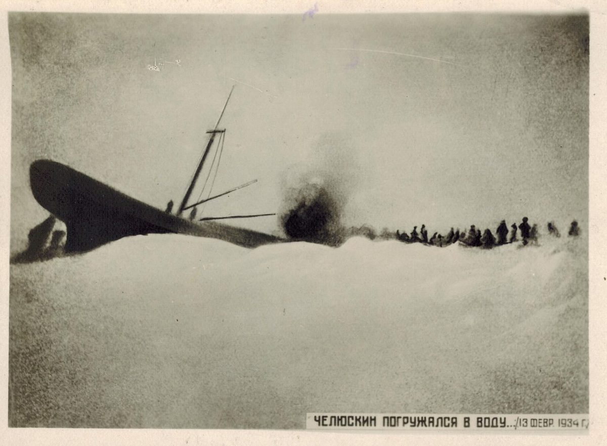 13 февраля 1934 года: корма «Челюскина» с мачтой торчит из льда, рядом поднимается столб дыма, вдали цепочка людей на снегу