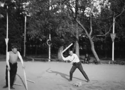 Фото 1935 года: игроки в городки в майках на песчаной площадке, один замахивается битой